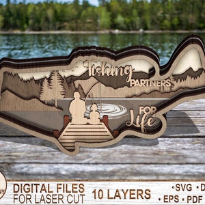 May include: A wooden layered cutout of a bass fish with a lake scene and two figures fishing from a dock. The text "Fishing Partners for Life" is included in the design. This is a digital file for laser cutting.
