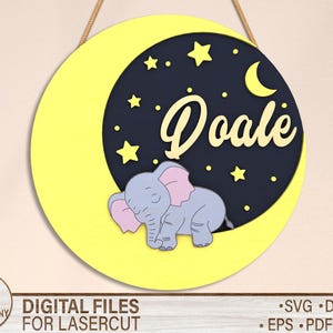 May include: A yellow circle with a crescent moon and stars in the center. A sleeping elephant with pink ears is on the moon. The text "Doale" is written in a yellow font on the moon.