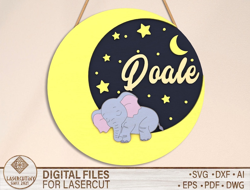 May include: A yellow circle with a crescent moon and stars in the center. A sleeping elephant with pink ears is on the moon. The text "Doale" is written in a yellow font on the moon.