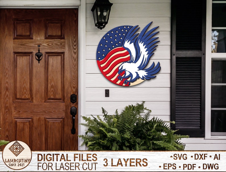 May include: A three-layer laser cut design of an American bald eagle with wings spread, holding the American flag in its talons. The design is in red, white, and blue colors and is suitable for a patriotic home decor project.