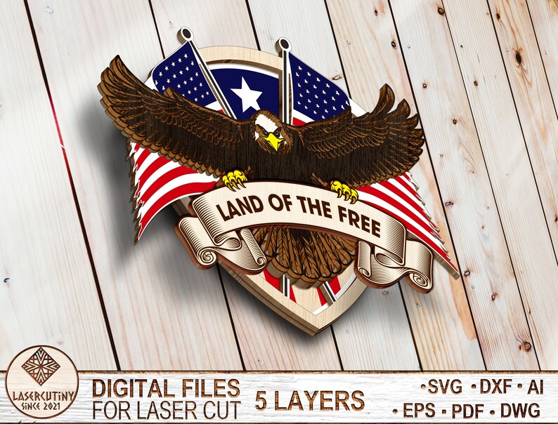 May include: A wooden cutout of an eagle with outstretched wings holding a scroll with the text "LAND OF THE FREE". The eagle is positioned in front of two American flags and a shield with a star.