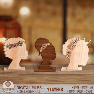 May include: Three wooden earring display stands featuring a silhouette of a woman's head with different hairstyles. Each stand has a floral design and holes for earrings. The stands are made of light and dark wood.