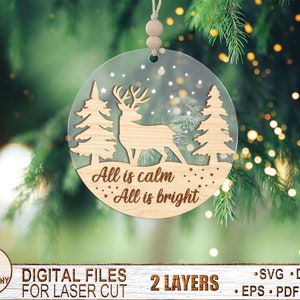May include: A laser cut wooden Christmas ornament featuring a deer standing in a snowy forest with the text "All is calm, All is bright".