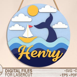 May include: A blue and yellow nautical themed wooden sign with the name "Henry" in yellow letters. The sign features a sailboat, a whale tail, and clouds against a blue background.