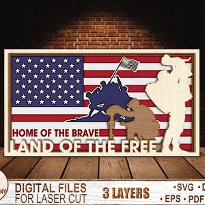 May include: A wooden sign with a layered design featuring an American flag, a soldier kneeling, and a soldier standing. The sign reads "Home of the Brave Land of the Free".