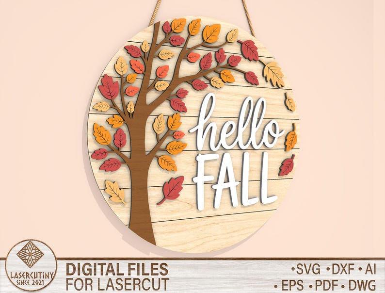 May include: A round wooden sign with a tree design and the words "hello FALL" in white. The tree has brown branches and colorful leaves in shades of red, orange, and yellow. The sign is hanging by a rope.