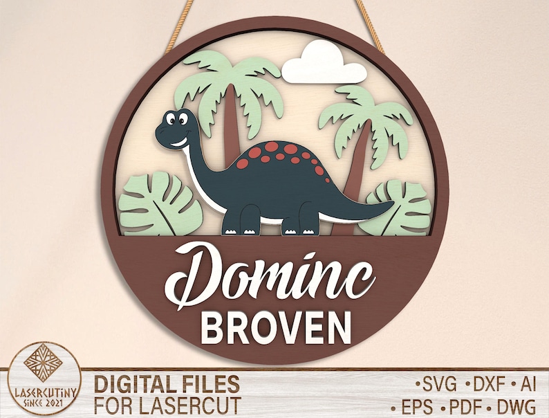 May include: A brown wooden circle with a dinosaur, palm trees, and leaves. The text "Dominc BROVEN" is written in white on the circle.