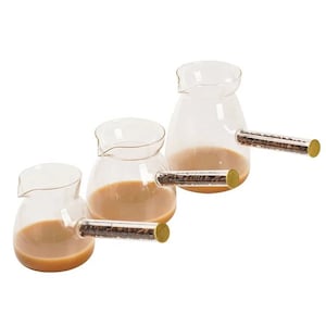 Könnte beinhalten: Drei Glas-Kaffeekannen mit klaren Glaskörpern und Griffen, die mit Kaffeebohnen gefüllt sind. Die Griffe sind klare Glasröhren, die mit Kaffeebohnen gefüllt sind.