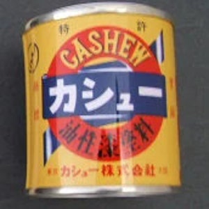May include: A yellow metal can with a blue and white label that says "CASHEW" in English and "カシュー" in Japanese. The label also says "油性塗料" in Japanese, which translates to "oil-based paint".