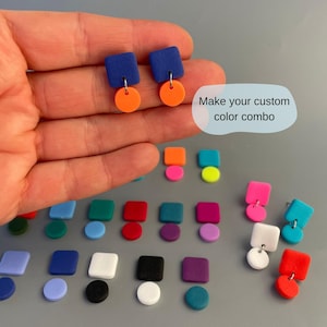 Könnte beinhalten: Eine Sammlung farbenfroher geometrischer Ohrringe. Die Ohrringe haben quadratische und kreisförmige Formen in verschiedenen Farben, darunter Blau, Orange, Pink und Grün. Der Text "Make your custom color combo" ist ebenfalls sichtbar.
