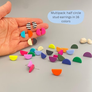 Könnte beinhalten: Eine Sammlung von Halbkreis-Ohrsteckern in verschiedenen Farben, darunter Rosa, Blau, Gelb und Grün. Einige Ohrringe haben schwarz-weiß gestreifte Muster. Der Text "Multipack: half circle stud earrings in 16 colors" ist enthalten.