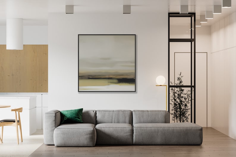 May include: A gray sectional sofa with a green velvet pillow in a modern living room with a framed abstract painting on the wall and a floor lamp with a white globe.