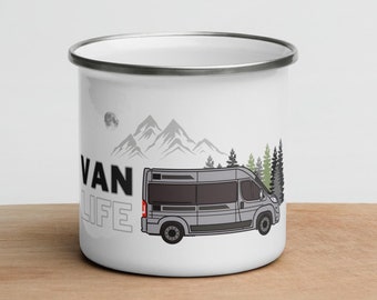 Puede incluir: Taza de esmalte blanco con una ilustración en negro y gris de una furgoneta de camping frente a montañas y árboles. El texto "VAN LIFE" está impreso en la taza.