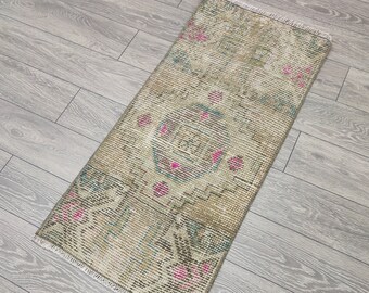 May include: A vintage runner rug with a faded floral pattern in shades of pink, green, and beige. The rug has a fringed edge and is made of wool.