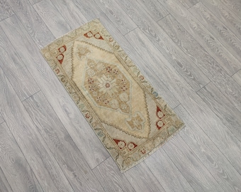 May include: A small, rectangular rug with a beige background and a red, brown, and blue floral pattern. The rug has a distressed, vintage look.