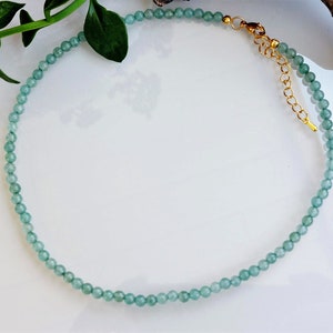 Puede incluir: Un delicado collar de piedras preciosas verdes con cierre de oro. El collar está hecho de pequeñas cuentas redondas y es perfecto para superponer.