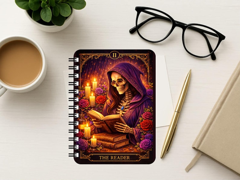 Puede incluir: Un cuaderno de espiral con una ilustraci&oacute;n estilo tarot de un esqueleto con t&uacute;nica morada con capucha leyendo un libro. La imagen incluye velas encendidas, rosas rojas y moradas, y el texto THE READER en la parte inferior en letras doradas.