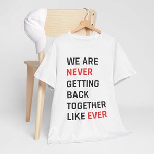 May include: White t-shirt with black text that reads "We are never getting back together like ever". The word "never" and "ever" are in red.