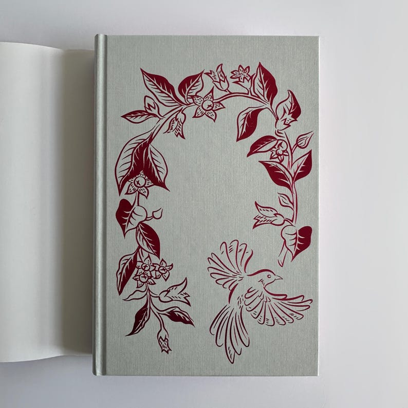 May include: A book cover with a red floral design and a red bird in flight. The background is a light gray.