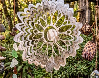 May include: A collection of hanging ornaments including a central silver-toned metal mandala wind spinner, a strand of smooth river stones, a strand of multi-colored sea glass, and a mobile featuring dried seed pods and a clear crystal prism.