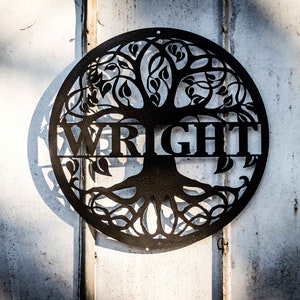 May include: Black metal tree of life wall art with the name "WRIGHT" inscribed in the center.