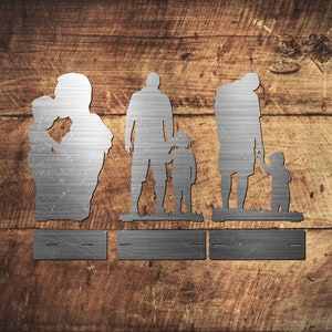Pu&ograve; includere: Arte da parete in metallo con silhouette di una famiglia di quattro persone. Le silhouette sono tagliate da una lamiera di metallo argentata e montate su uno sfondo di legno. La famiglia &egrave; raffigurata in un abbraccio amorevole, con i genitori che tengono i loro due figli.