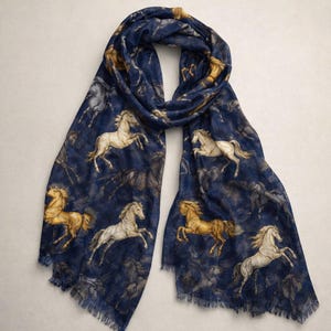 Puede incluir: Bufanda azul marino con un estampado repetido de caballos en tonos dorados, blancos y grises. La bufanda tiene un borde con flecos y está hecha de un material suave y ligero. El diseño presenta caballos en varias poses.
