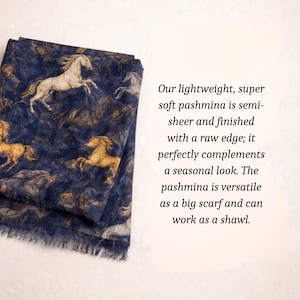 May include: Navy blue pashmina scarf with a repeating pattern of tan and white horses. The scarf has a raw edge and is semi-sheer. The text on the image says, "Our lightweight, super soft pashmina is semi-sheer and finished with a raw edge; it perfectly complements a seasonal look. The pashmina is versatile as a big scarf and can work as a shawl."