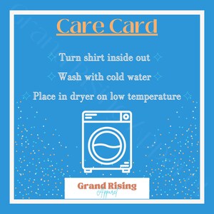 May include: A blue care card with white text and a white outline of a washing machine. The text reads "Care Card", "Turn shirt inside out", "Wash with cold water", and "Place in dryer on low temperature". The bottom of the card has the text "Grand Rising Apparel".