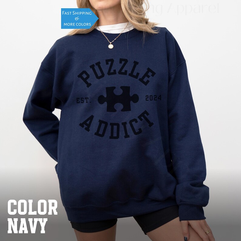 May include: Navy blue sweatshirt with a black graphic of a puzzle piece and the text "PUZZLE ADDICT EST. 2024".