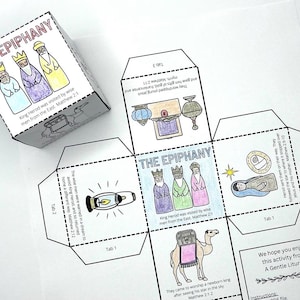 May include: A white, unfolded paper craft featuring illustrations and text about the Epiphany. The cube shows drawings of the three wise men, a camel, and other religious symbols. The text includes Bible verses.