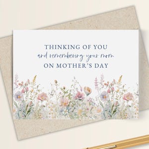 Op de afbeelding: Een Moederdagkaart met een bloemenontwerp en de tekst "Thinking of you and remembering your mom on Mother's Day". De kaart ligt op een kraftpapieren envelop, met een gouden pen in de buurt.
