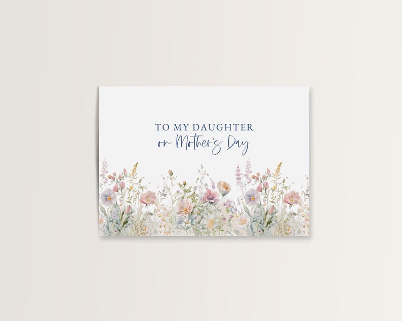 May include: A white greeting card with the text "TO MY DAUGHTER on Mother's Day" in blue script. The bottom of the card features a watercolor illustration of delicate pink, purple, and yellow flowers and greenery.