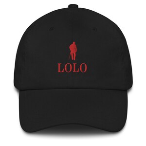 May include: Black baseball cap with a curved brim. The cap features red embroidered text that reads "LOLO" below a red embroidered silhouette of a person holding a staff. The cap is made of a soft fabric.
