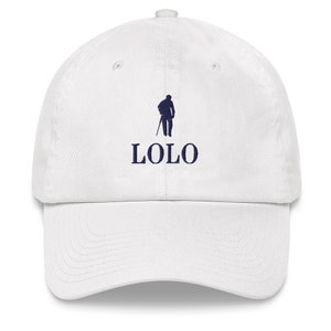 May include: White baseball cap with a curved brim. The cap features a navy blue silhouette of a person with a cane and the word "LOLO" in navy blue, centered below the graphic. The cap is made of a soft, durable material.