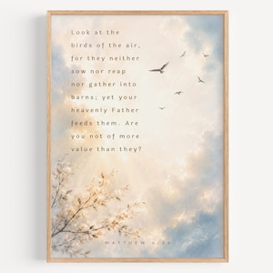 Op de afbeelding: Een rechthoekige wandkunstprint in een lichthouten lijst met een zachte blauwe en witte bewolkte lucht, vliegende vogels, witte bloeiende takken onderaan en de tekst Matthew 6:26 met het volledige bijbelvers.