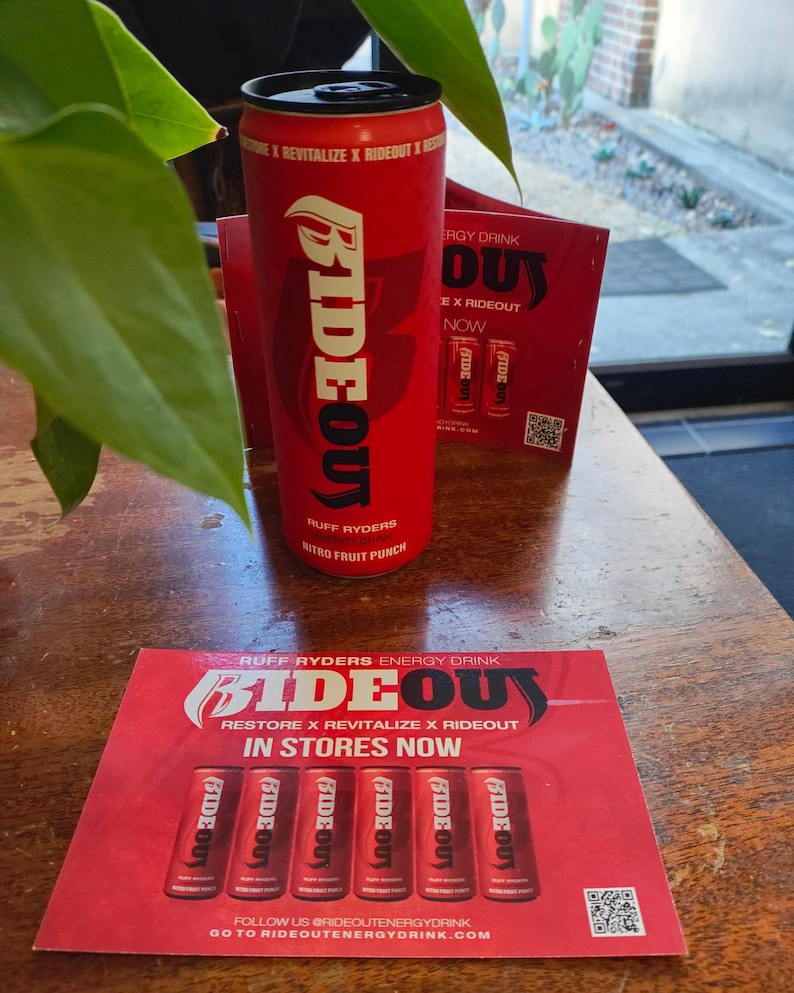 May include: Red and black energy drink can with the words "Ride Out" and "Ruff Ryders" on it. The can is sitting on a red and white flyer that says "Ride Out Energy Drink" and "Restore x Revitalize x Ride Out".