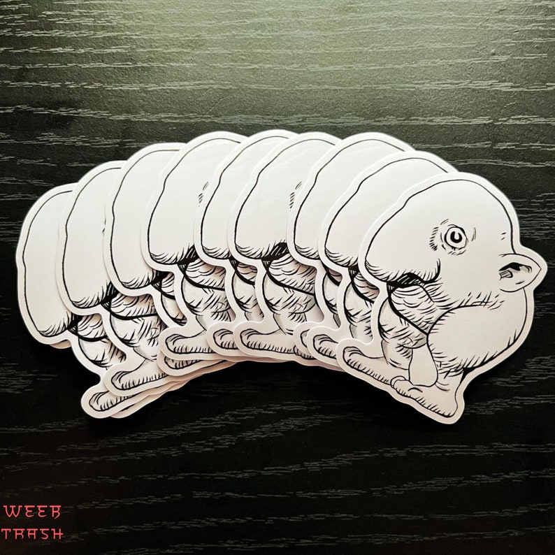 May include: A set of eight white vinyl stickers featuring a cartoon creature with a large head and a small body. The creature has a large eye and a small mouth. The stickers are arranged in a row, with the creature's heads facing the same direction.