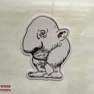 May include: A black and white line drawing of a small, round, humanoid creature with a large nose and one eye. The creature is standing on two legs and has a small ear on the side of its head.