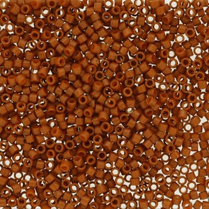 May include: A large collection of small, cylindrical, matte brown beads arranged in a dense, uniform layer. Each bead features a central hole, creating a consistent, repetitive pattern across the entire surface of the image.