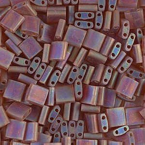 May include: A mix of iridescent purple and brown square and rectangular glass beads. The beads have two holes each.