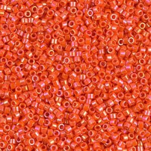 May include: Close-up of a pile of small, orange, cylindrical beads. The beads have a slightly iridescent finish, reflecting hints of pink and gold. These beads are likely used for jewelry making or other craft projects.