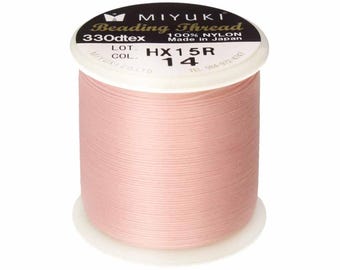 May include: A spool of light pink Miyuki beading thread made of 100% nylon. The label on the top reads Miyuki Beading Thread, 330dtex, 100% Nylon, Made in Japan, with color code HX15R 14 printed clearly on the white circular top surface.