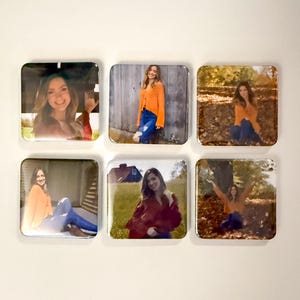 May include: Six square photo magnets featuring a person in various outdoor settings. The person is wearing an orange sweater and blue jeans in several of the photos. The magnets are arranged on a white wall.