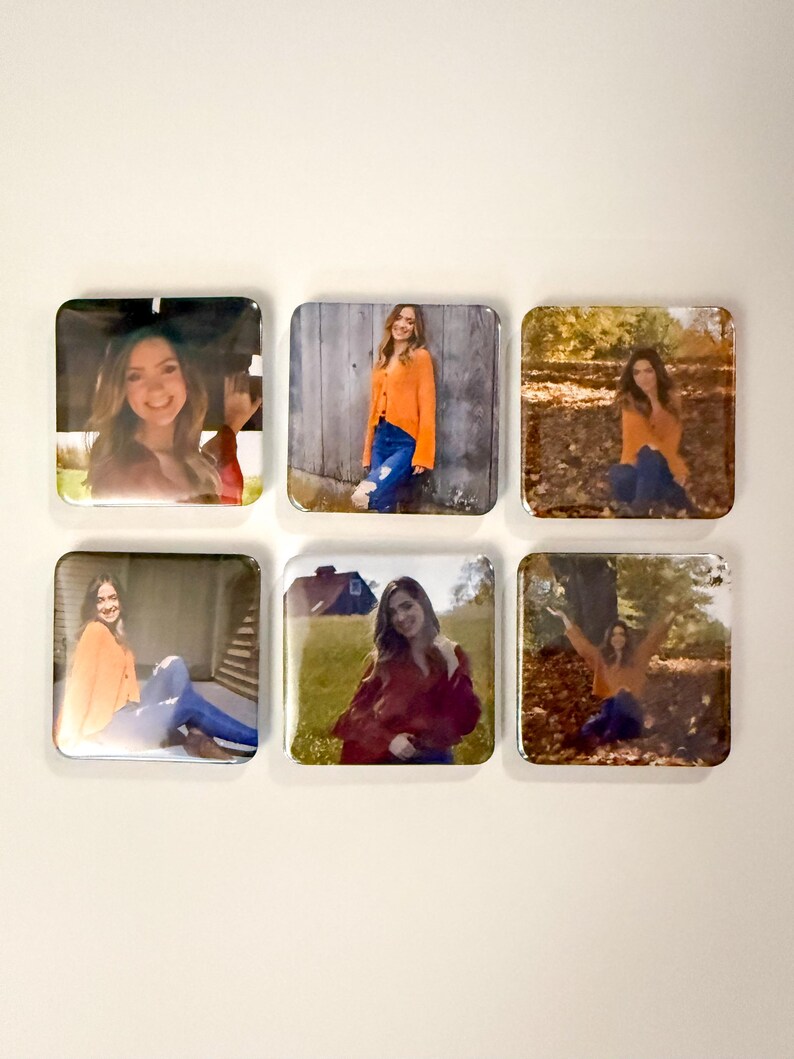 May include: Six square photo magnets featuring a person in various outdoor settings. The person is wearing an orange sweater and blue jeans in several of the photos. The magnets are arranged on a white wall.