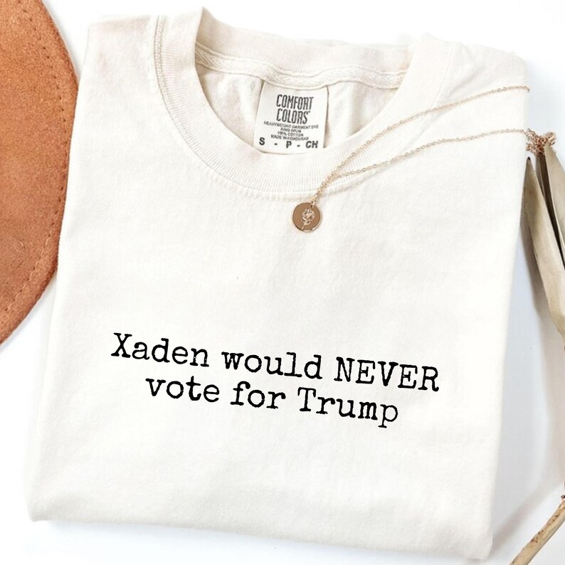 May include: A white t-shirt with the text "Xaden would NEVER vote for Trump" printed in black.