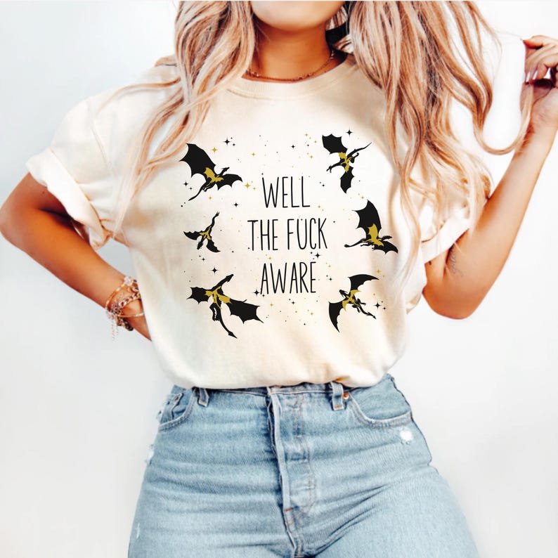 May include: A white t-shirt with a black graphic of dragons and the text "Well the fuck aware".