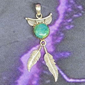 May include: A silver pendant with a green turquoise stone and two silver feathers hanging from it.