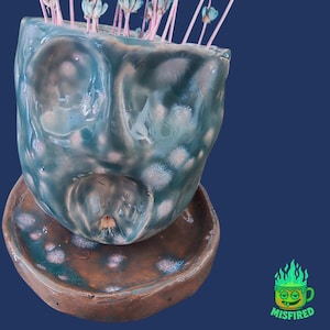 May include: A white ceramic mug with a black handle and the text "But First, Coffee" in a bold, black font. The mug is set against a neutral background, highlighting its simple design.