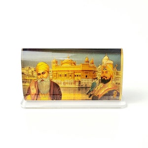 May include: A framed image of two Sikh men in front of a golden temple. The men are wearing traditional turbans and robes. The temple is ornate and has a golden dome.